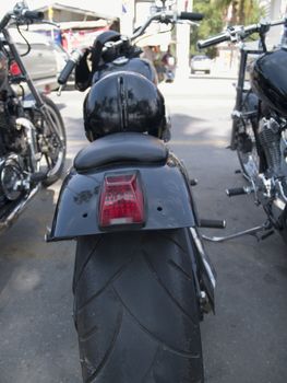 Rear end of black, custom built motorcycle with very wide tire. Shallow depth of field.