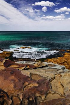 Ocean view with rocks, cloudy skies and azure water