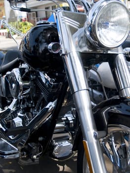 Front and headlight of black and chrome, custom built motorcycle. Shallow depth of field.