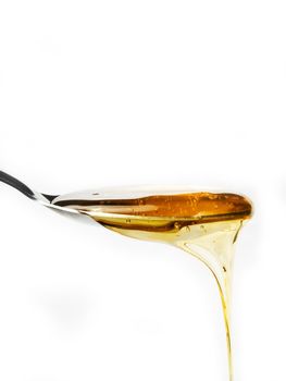 Honey on a spoon over a white background