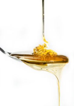 Honey on a spoon over a white background