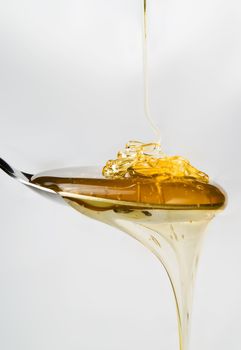 Honey on a spoon over a white background