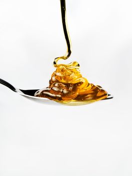 Honey on a spoon over a white background