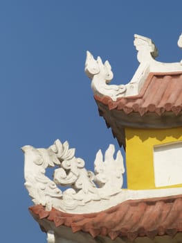 Detail of ancient, yellow Asian building on a blue sky background.