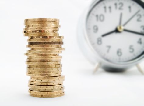 Pile of coins and alarm clock on a white background