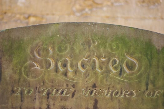 Grave stone with the word "sacred",  lot of stone texture visible.