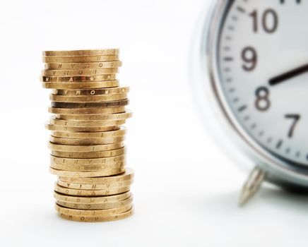 Pile of coins and alarm clock on a white background