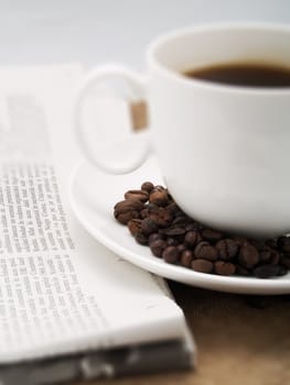 Coffee cup with coffee beans and a newspaper