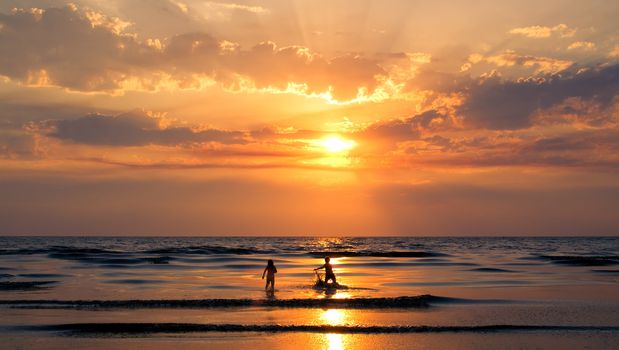 Playing children in a sunset over sea