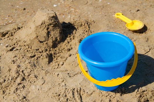 Blue bucket and yellow spade on a beach