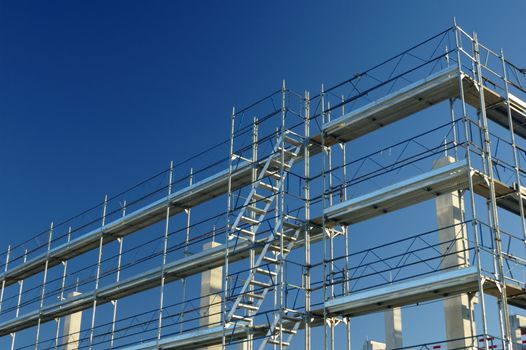 Scaffolding on a construction site, against a clear blue sky.