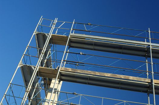 Scaffolding on a construction site, against a clear blue sky.