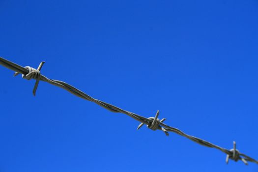 Close up of a barbed wire over blue sky.
