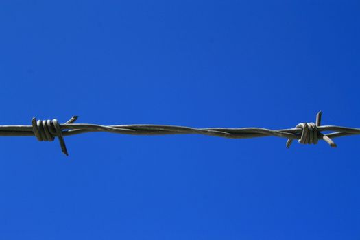 Close up of a barbed wire over blue sky.
