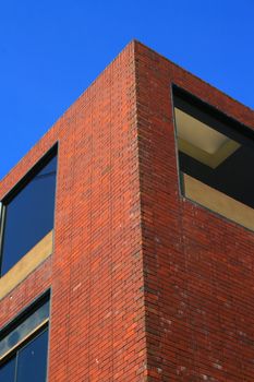 Corner of a brick building over blue sky.
