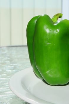 Close up of a green bell pepper on a plate.
