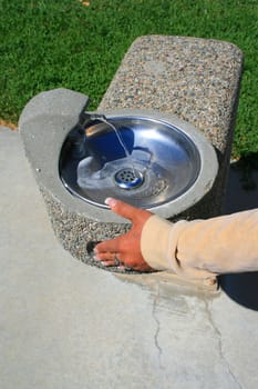 Close up of a hand pushing water fountain.

