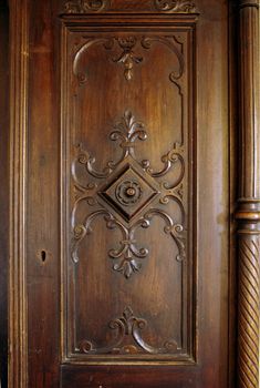 A picture of a wooden carved door of an antique closet