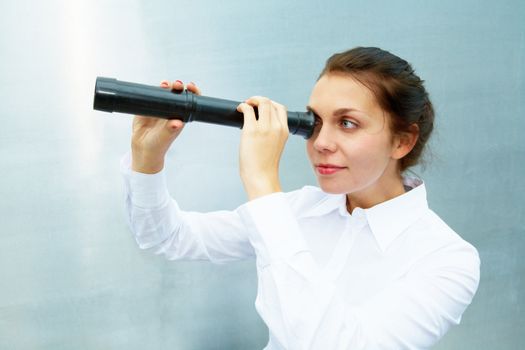 Young woman using telescope outside building wall