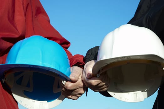 two hard-hats (blue and white color) focus on hand of man