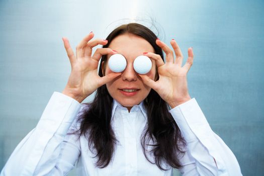 Young woman holding golf balls over eyes