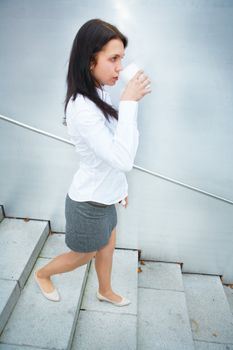 Young woman drinking coffee on stairs