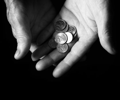 old hands with coins on black background