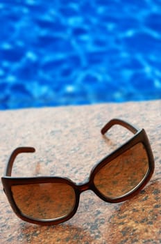 sun glasses and blue pool(focus point on the right lower part of sun glasses)