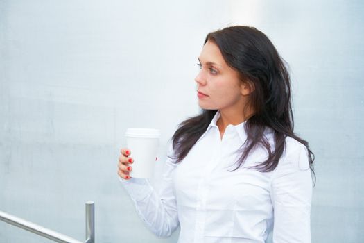 Young woman holding coffee cup outside building