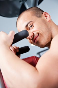 Close-up of an attractive male working out at the gym, looking at the camera