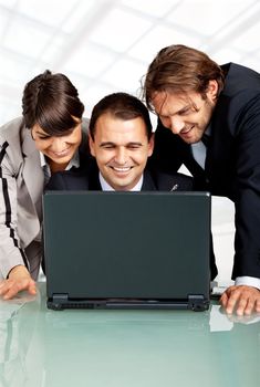 three happy businesspeople with a laptop, laughing