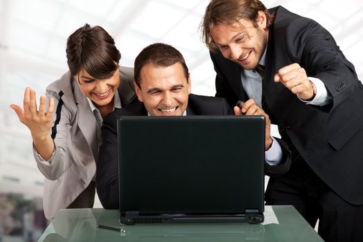 three businesspeople gesturing and smiling over a laptop