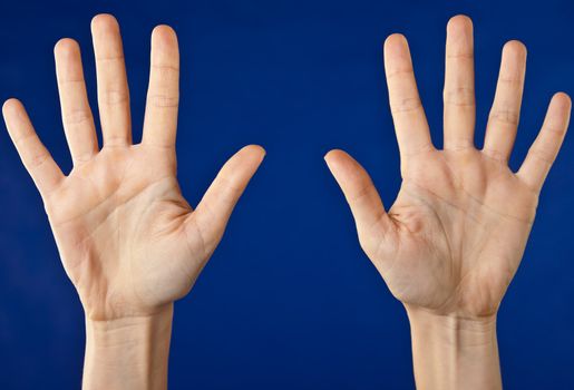 Close-up of two hands with open palms on blue background