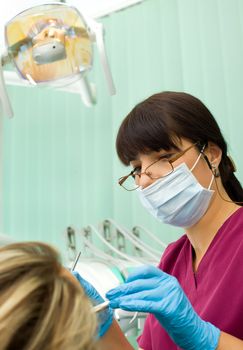 Female dentist wth protection mask and gloves working on patient