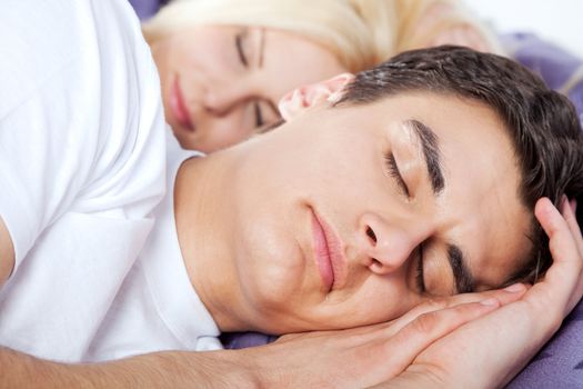 Close-up of a young couple sleeping late together, man on focus