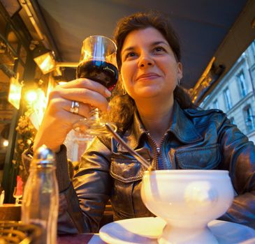 Beautiful smiling woman sitting in restaurant, holding glass of red wine