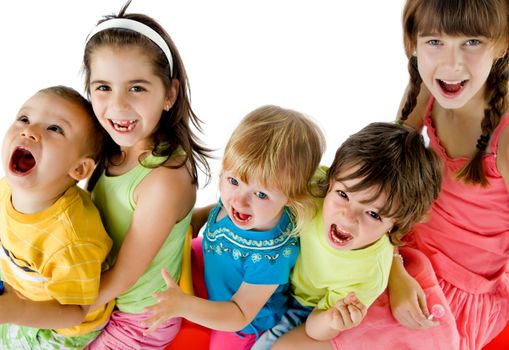 Group of five happy kids sitting, smiling and screaming looking up at camera