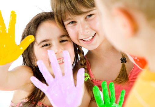 Close-up of two little girls showing their painted colourful hands to a boy, focus on girls