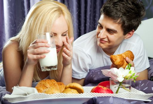 young woman and a man having breakfast in bed