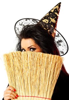 young female dressed up as a witch hiding behind broom