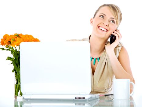 Beautiful happy female sitting behind desk with laptop, talking on the phone