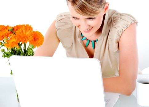 Beautiful happy woman sitting behind desk with laptop, looking at screen
