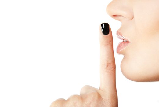 Close-up of female index finger with black fingernail put on her lips, making silence sign