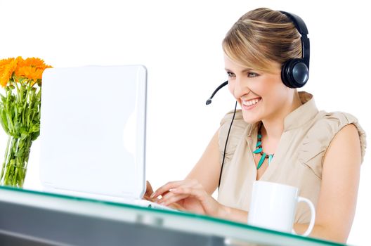 Beautiful happy female with headset sitting behind desk with laptop