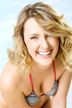 Close-up of happy beautiful blond woman in swimsuit, smiling at camera