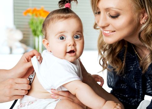 Sweet little baby girl in hospital being examinated and held by mother