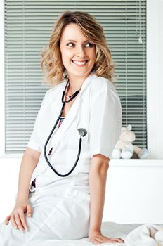 Beautiful smiling female doctor with stethoscope leaning on a couch
