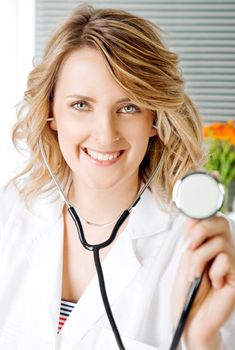 Close-up of beautiful blonde female doctor with stethoscope, smiling at camera