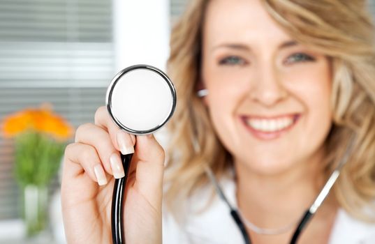 Close-up of stethoscope, being held by smiling female doctor, focus on instrument