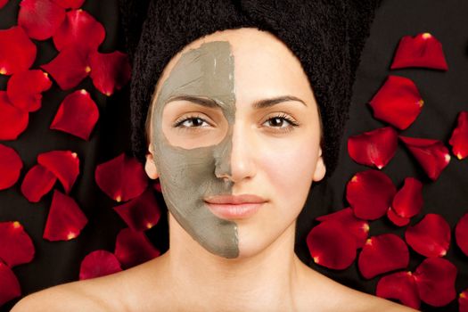 young beautiful woman having a clay mask on half of her face